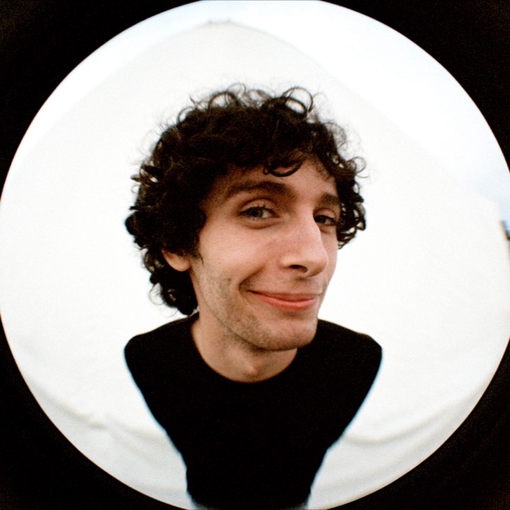 Fisheye portrait: a curly-haired man smirking
