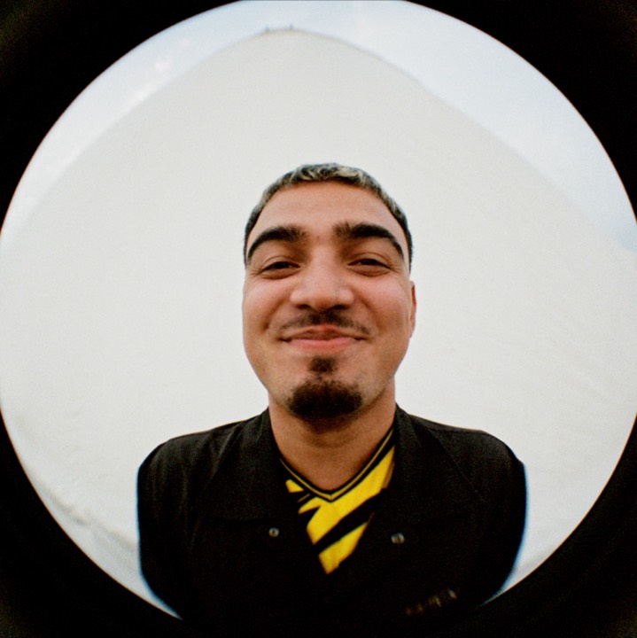 Fisheye portrait: a man in a yellow and black shirt, grinning