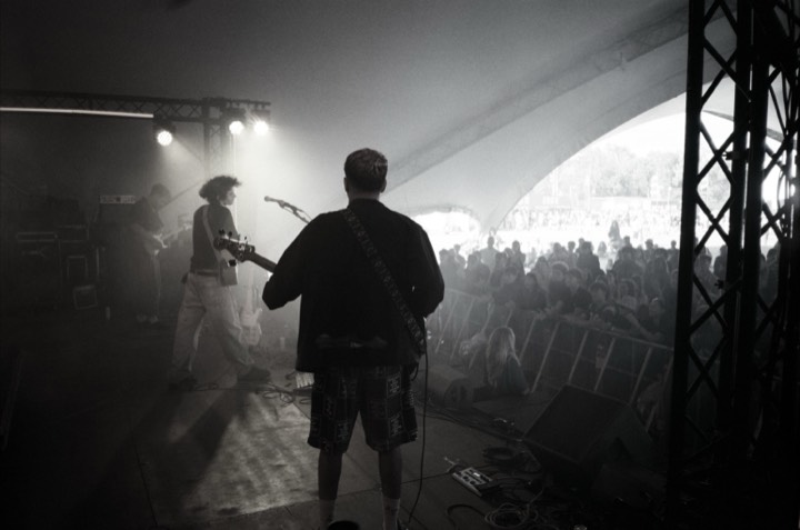 A guitarist backlit on stage, in black and white
