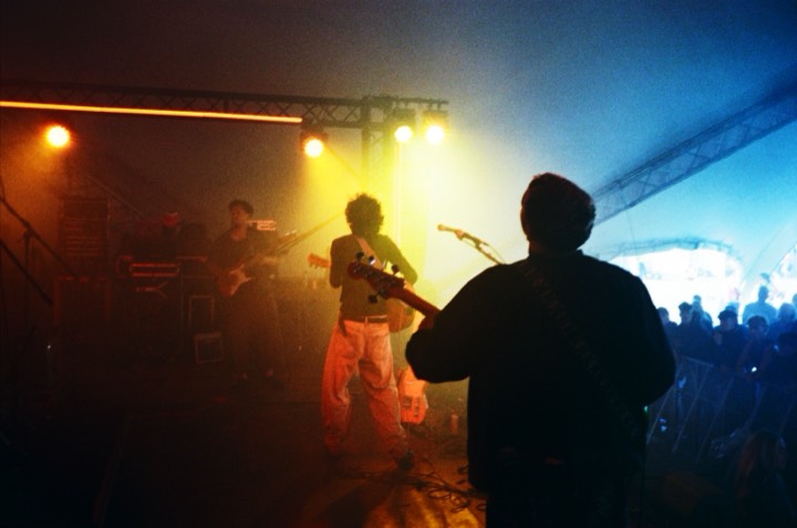 A guitarist in orange light, the crowd beyond